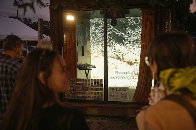 Visitors viewing projected artwork through the ArtCube window at night