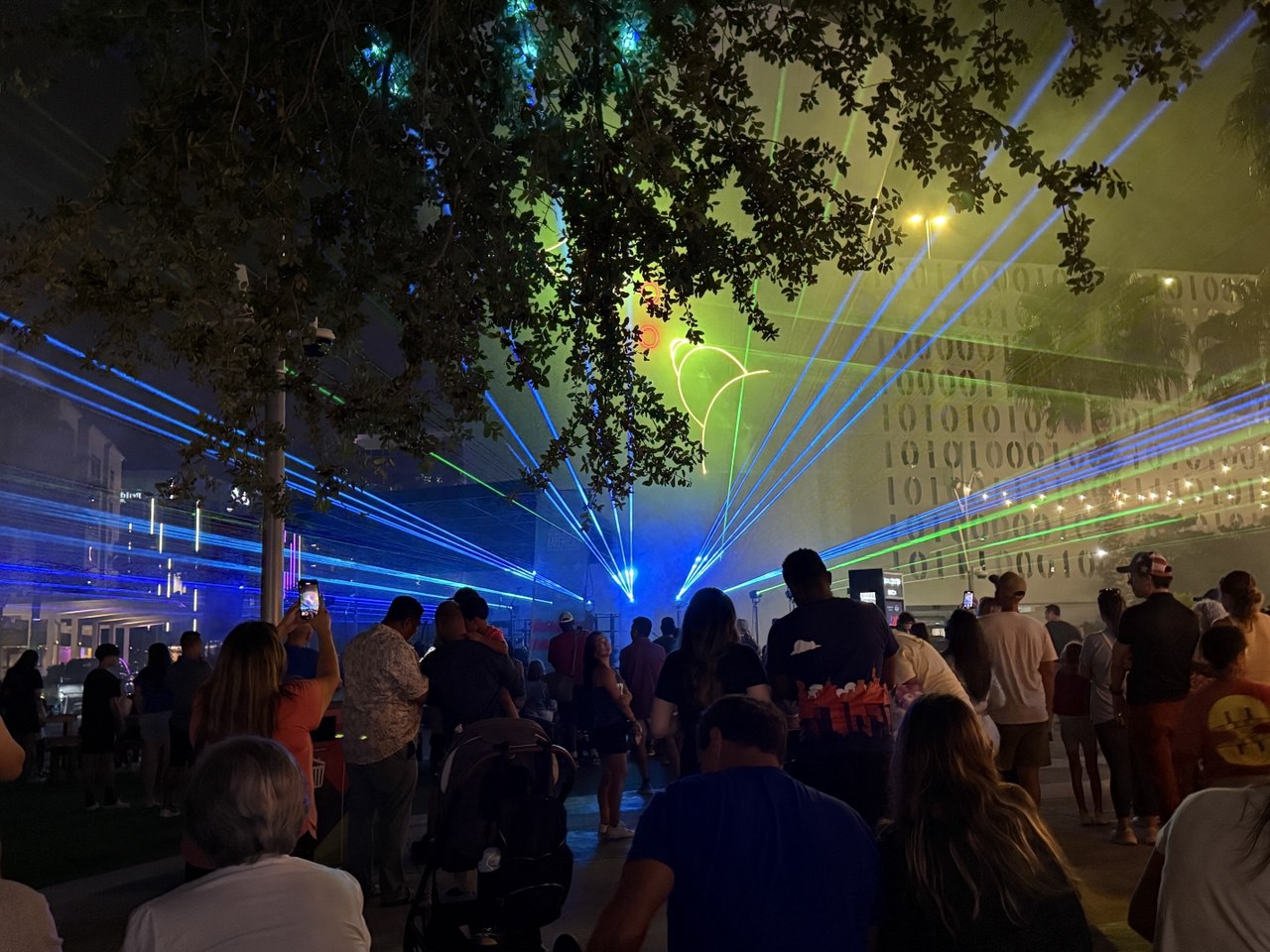 Blue and green lasers cutting through fog with binary code building in background